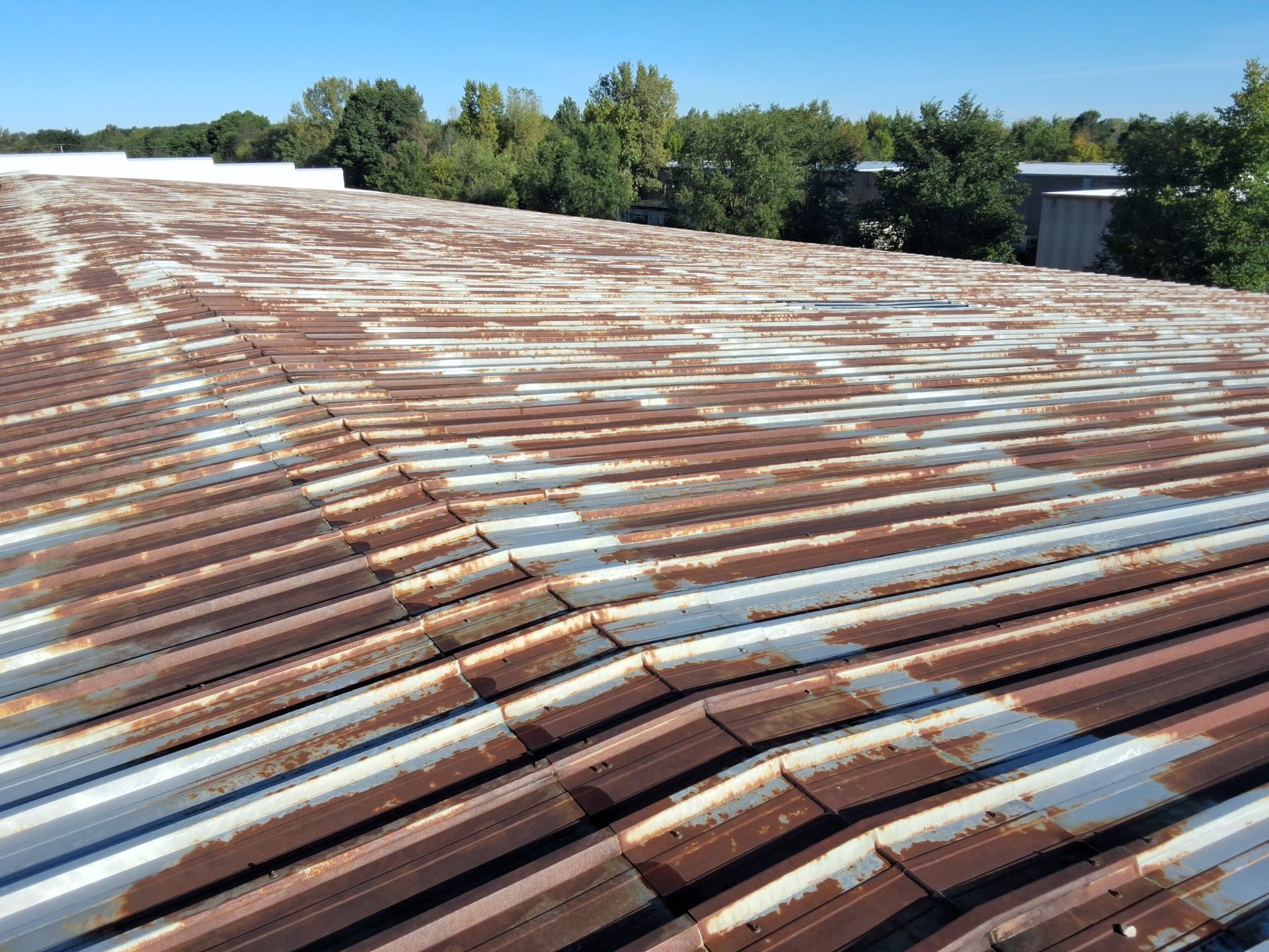 A rusty metal roof with a blue sky in the background.