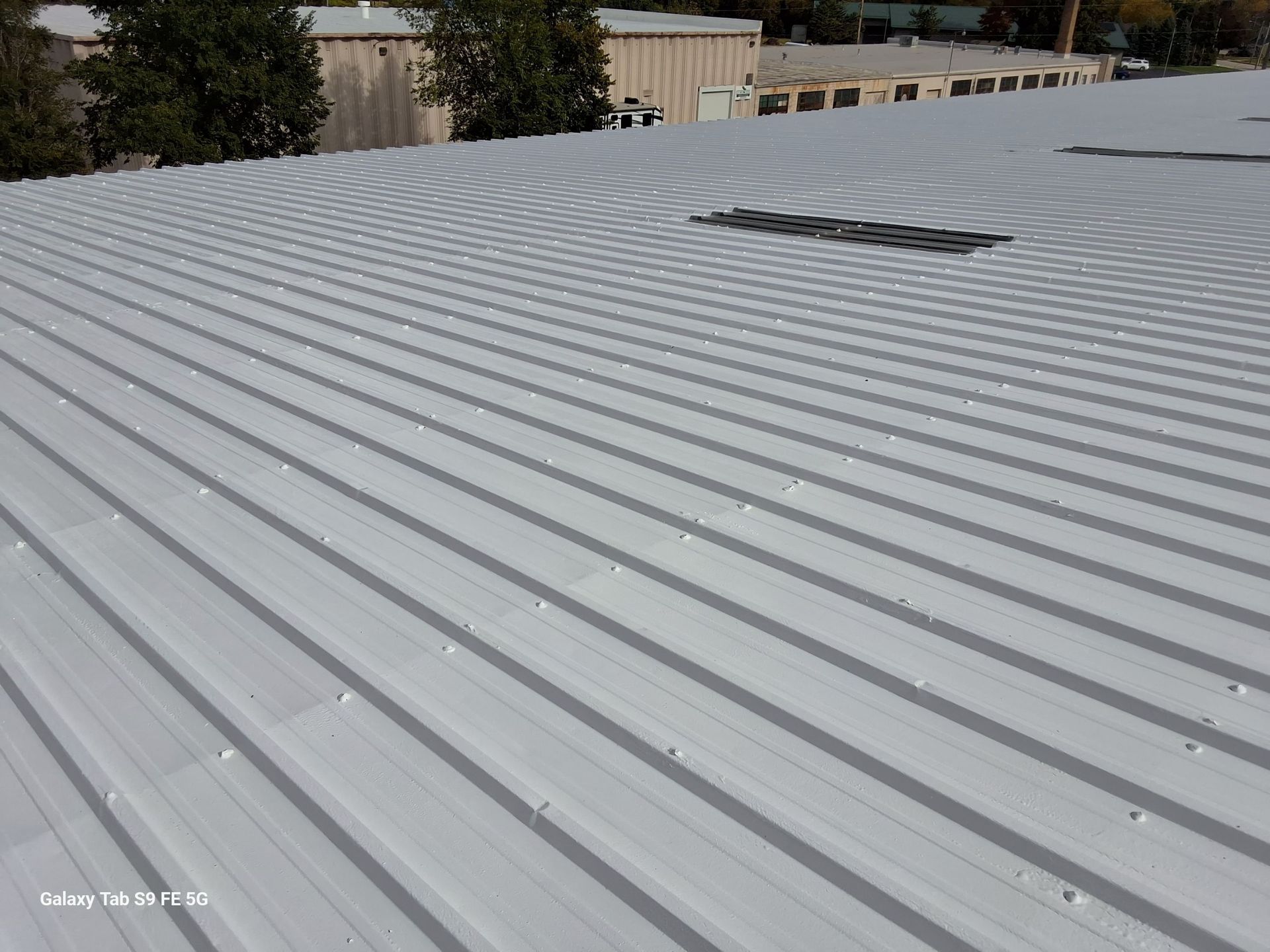 A white metal roof with a hole in the middle of it.