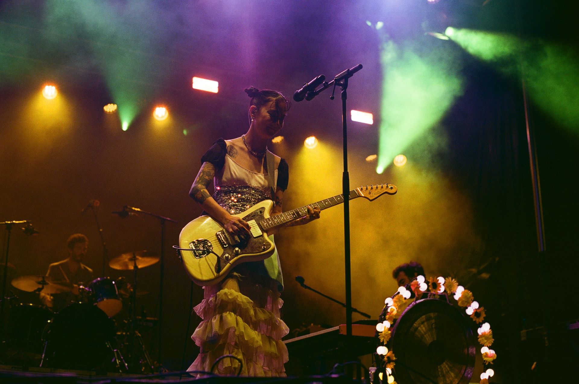 A woman is playing a guitar and singing into a microphone on a stage.