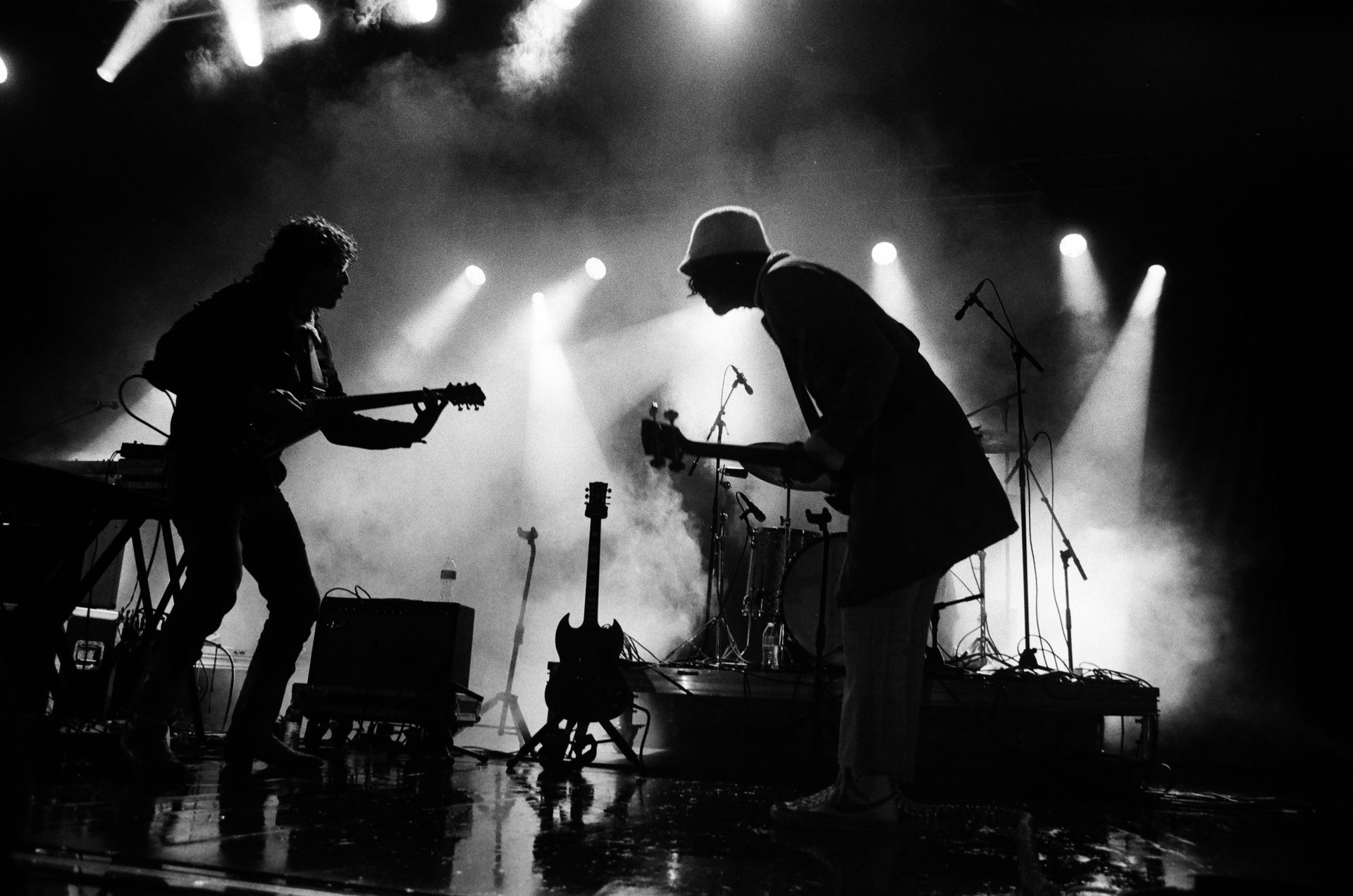Two men are playing guitars on a stage in a black and white photo.