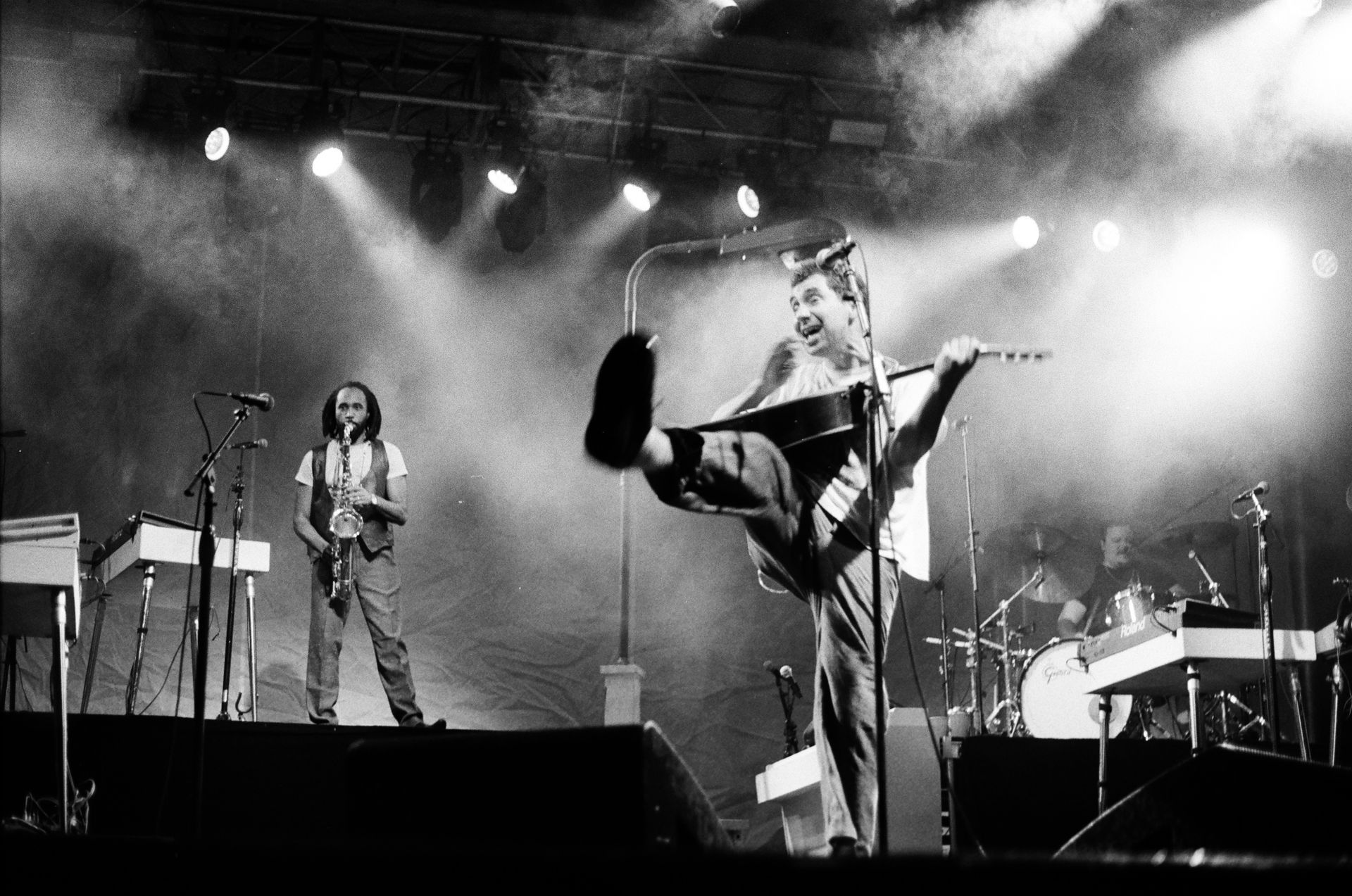 A black and white photo of a man singing into a microphone on a stage.