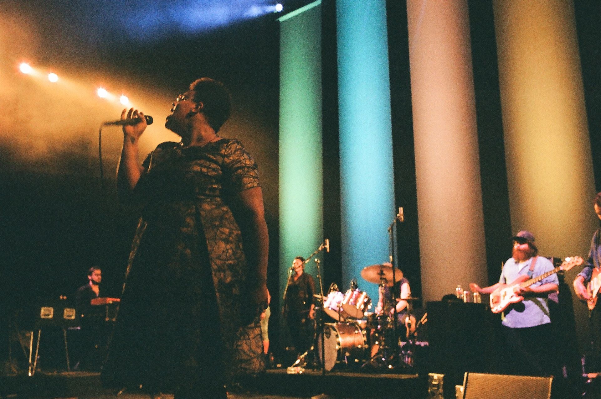 A woman singing into a microphone on a stage with a band behind her