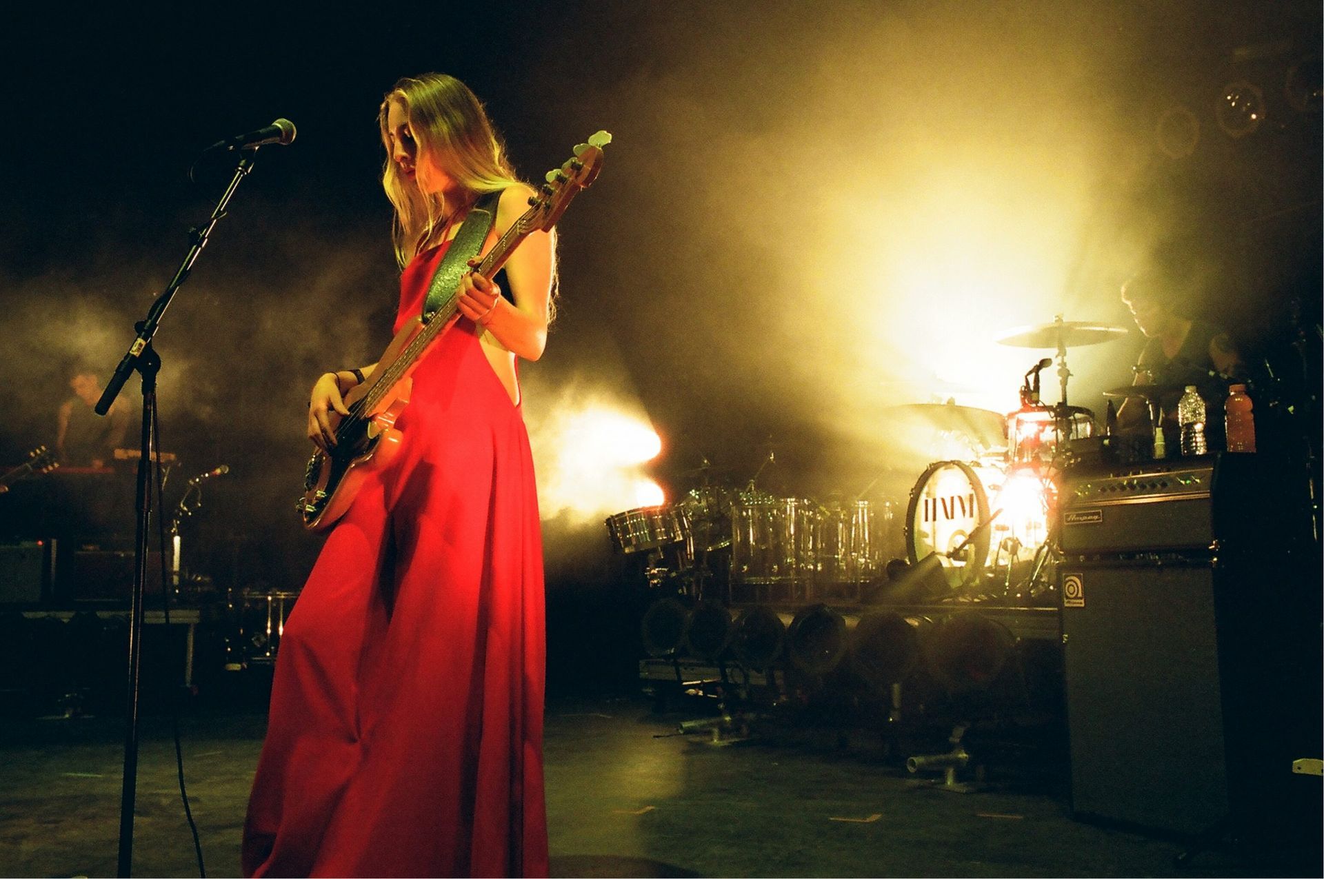 A woman in a red dress is playing a guitar on stage.