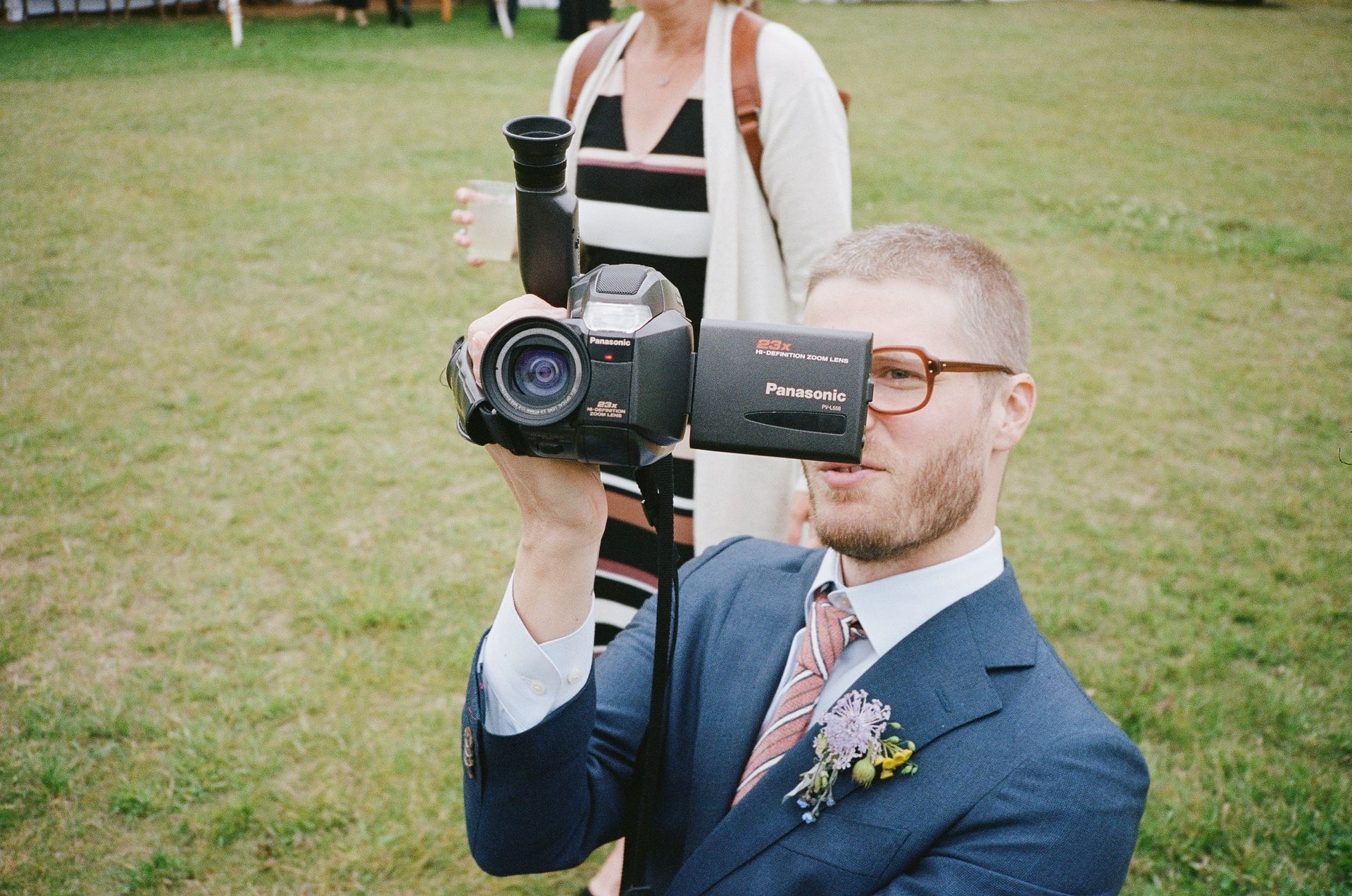 A man in a suit is taking a picture with a video camera.