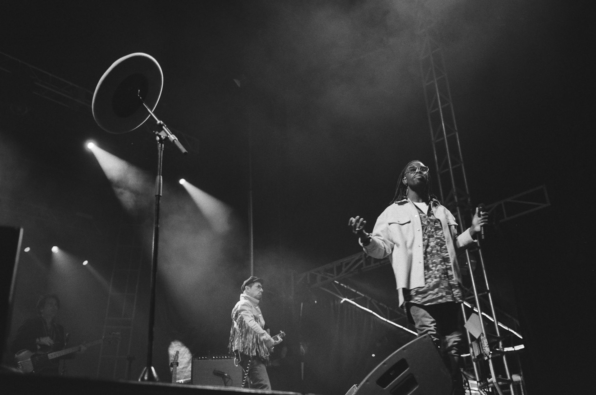 A black and white photo of a man singing into a microphone on a stage.