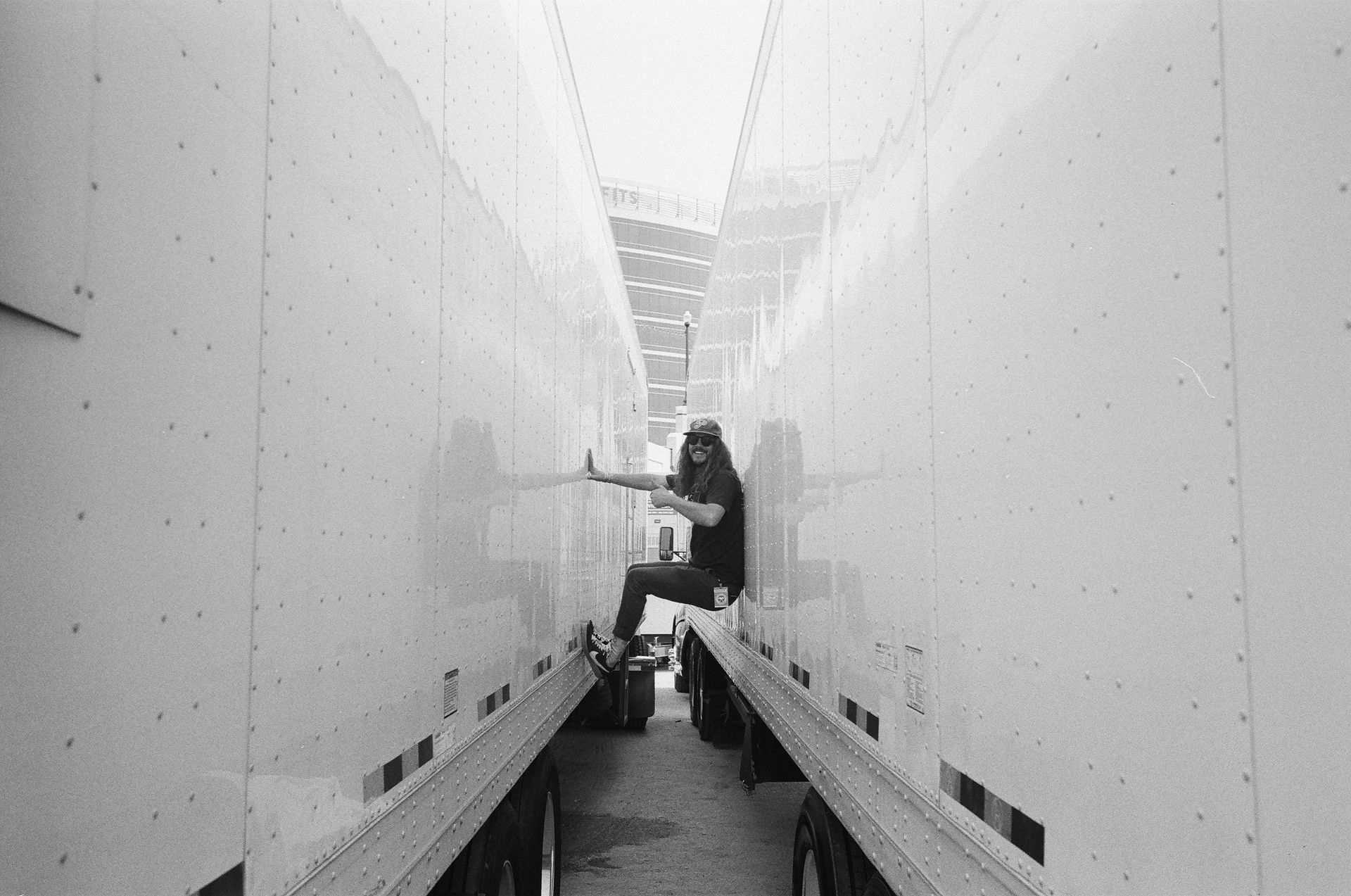 A man is sitting on the back of a semi truck.