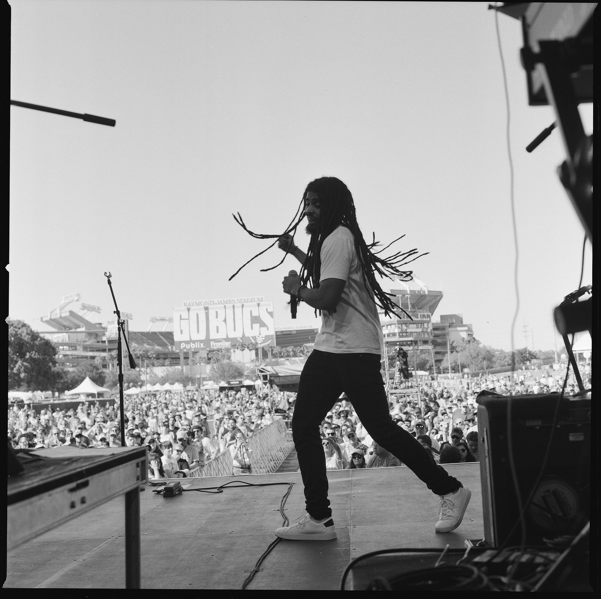 A man singing into a microphone in front of a sign that says go bucs