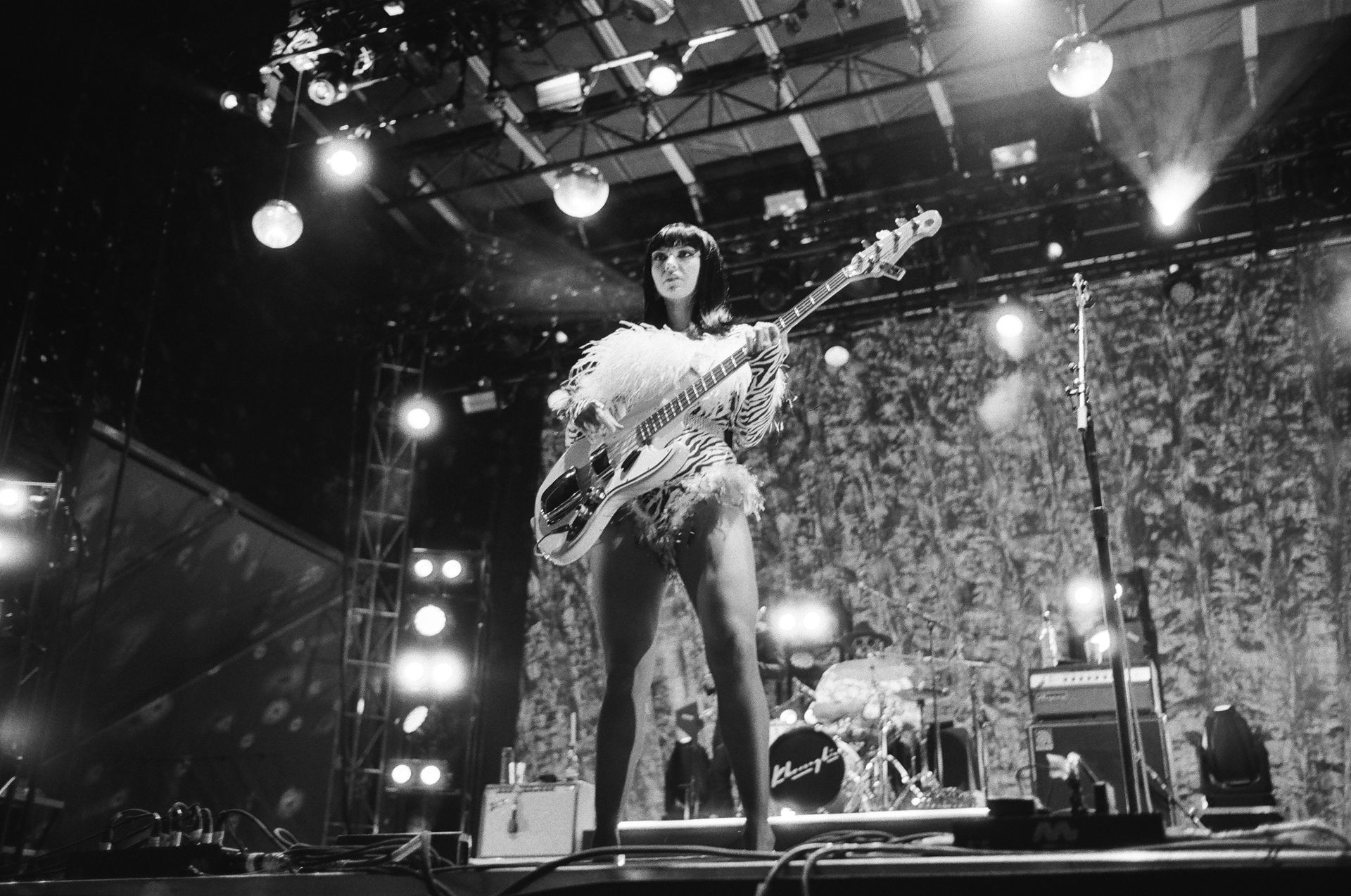 A woman is playing a guitar on a stage in a black and white photo.