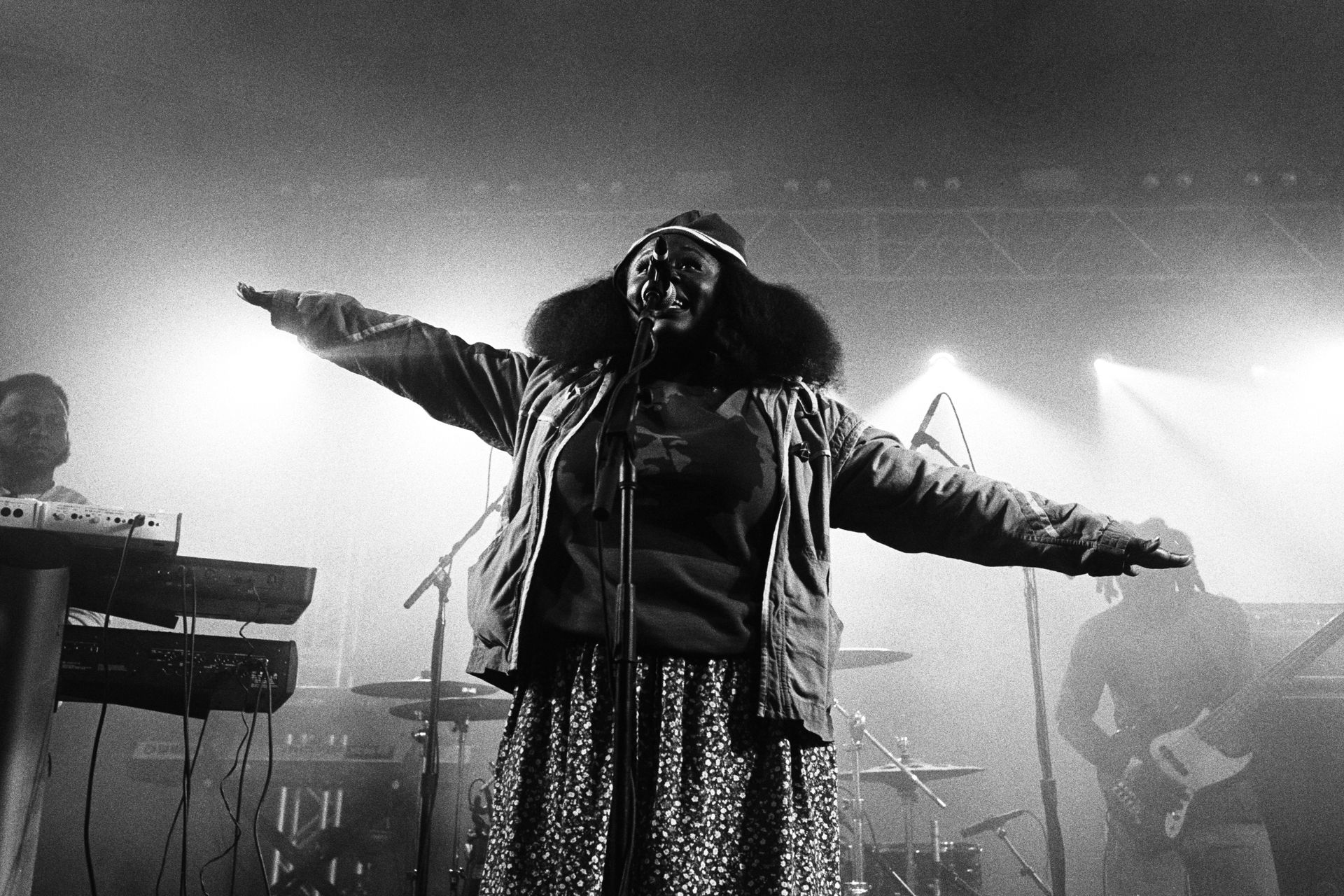 A woman singing into a microphone with her arms outstretched