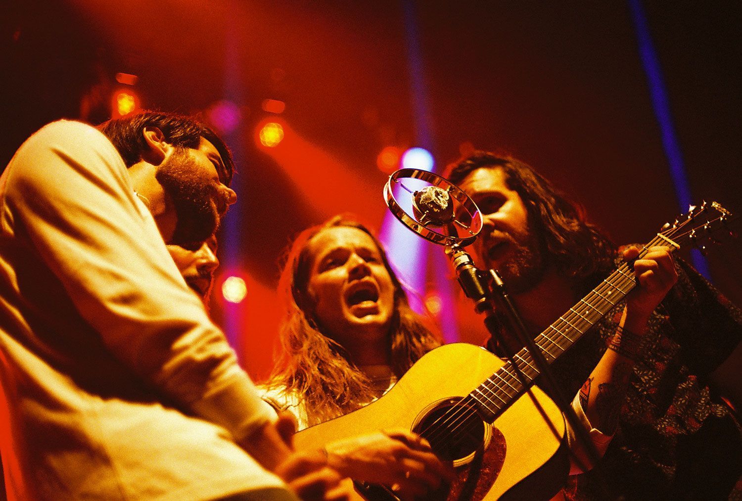 A group of people are singing and playing guitars on a stage.