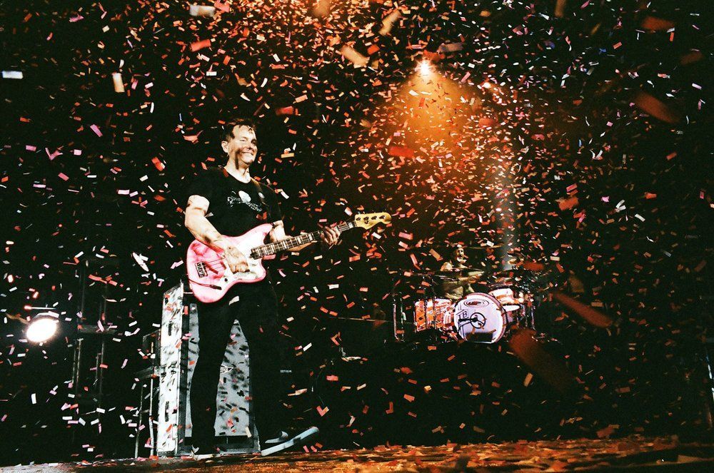 A man is playing a guitar on a stage surrounded by confetti.