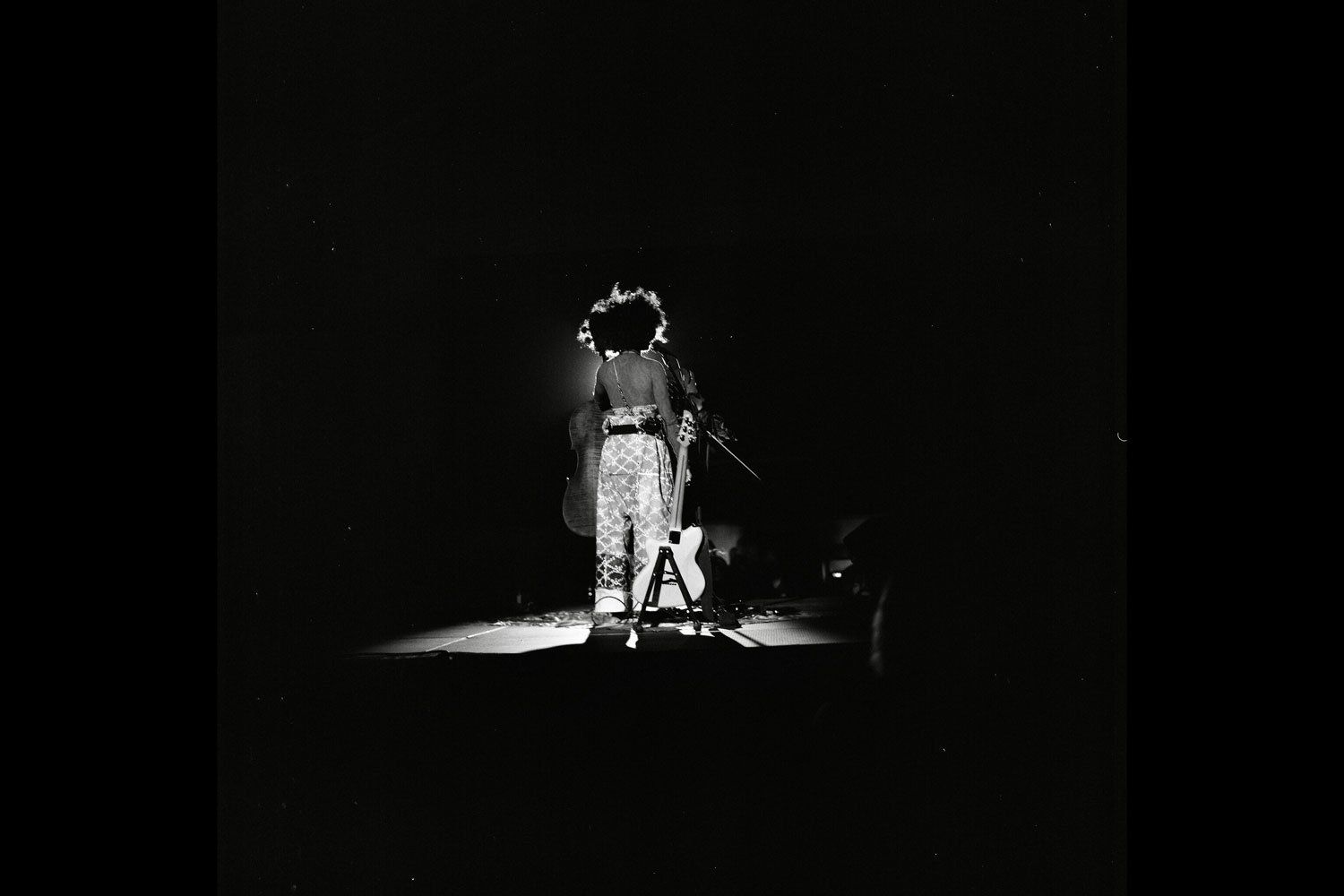 A black and white photo of a woman singing into a microphone on a stage.