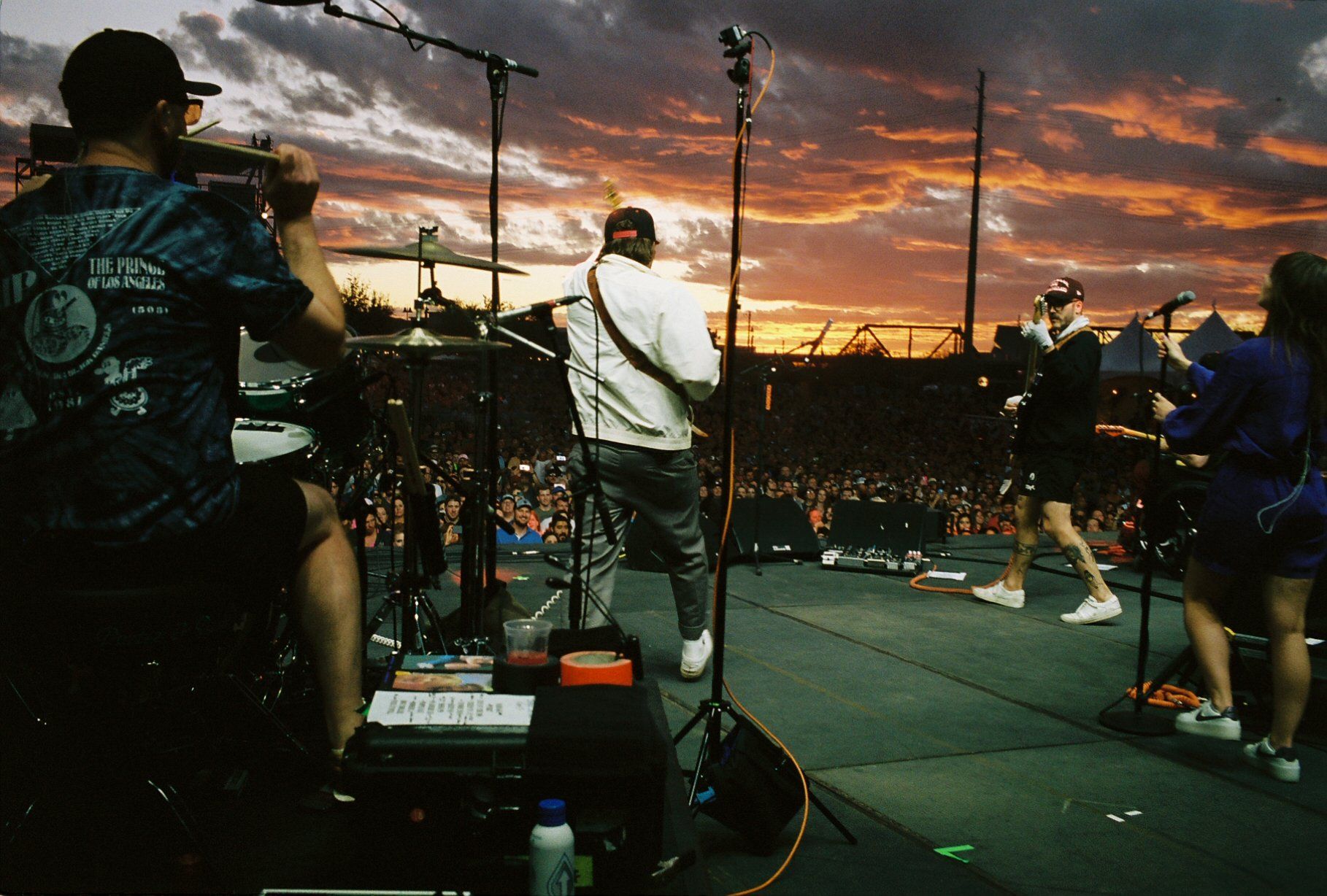 A group of people playing instruments on a stage at sunset