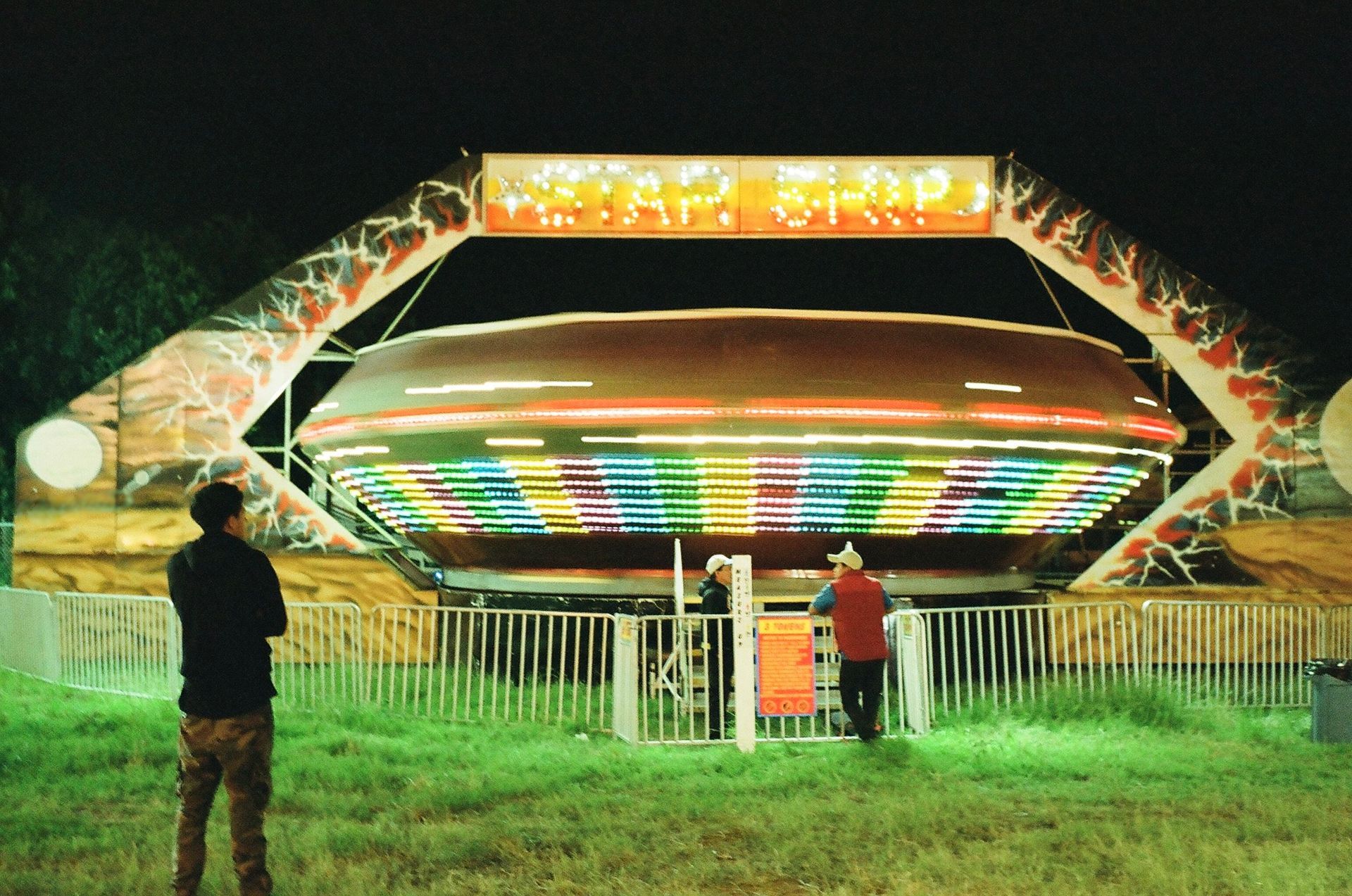 A man stands in front of a carnival ride that says yeah grip