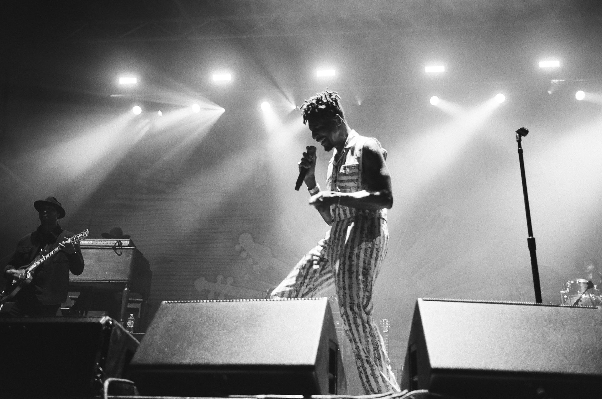 A black and white photo of a man singing into a microphone on a stage.