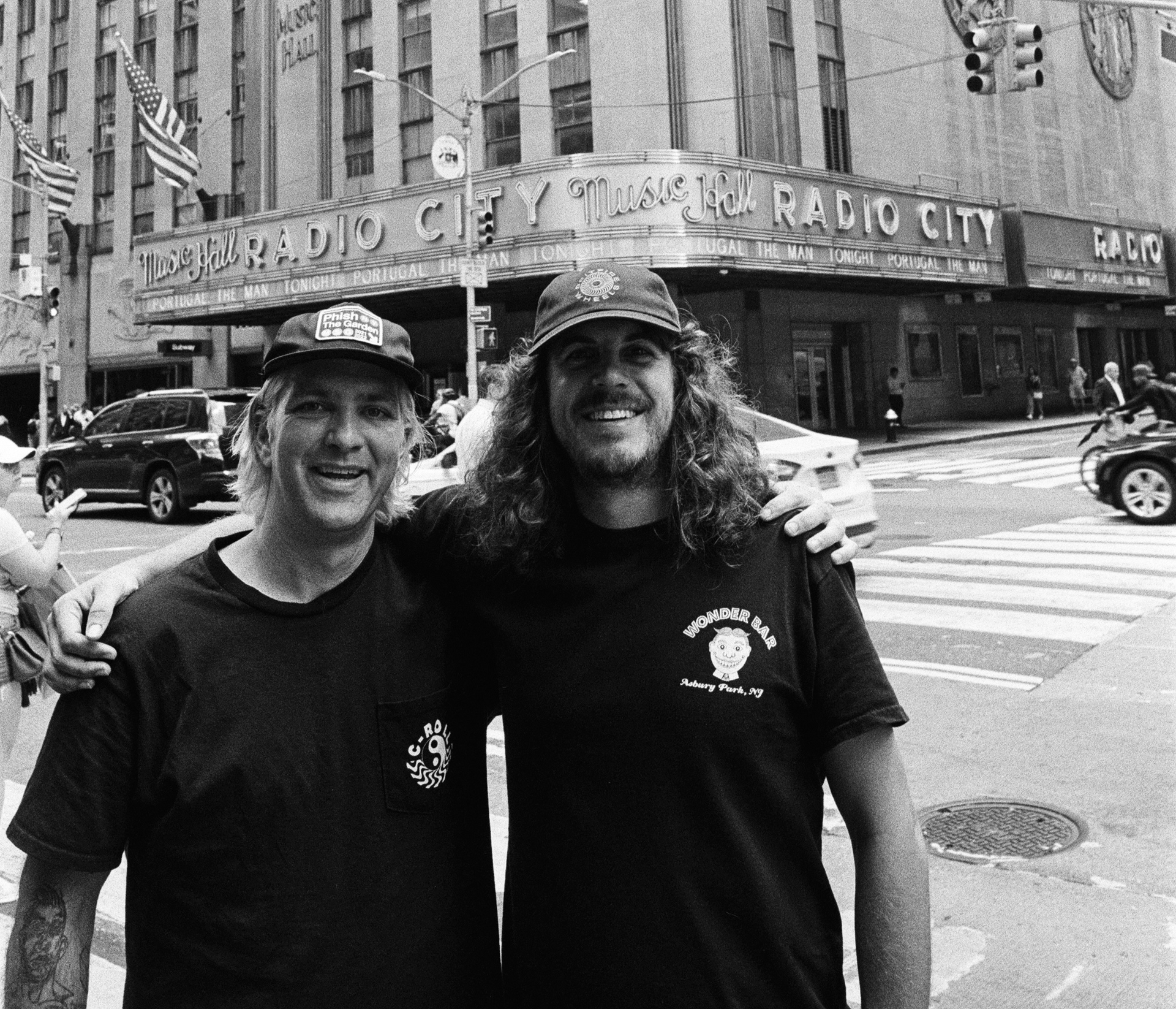 Two men are posing for a picture in front of the radio city building