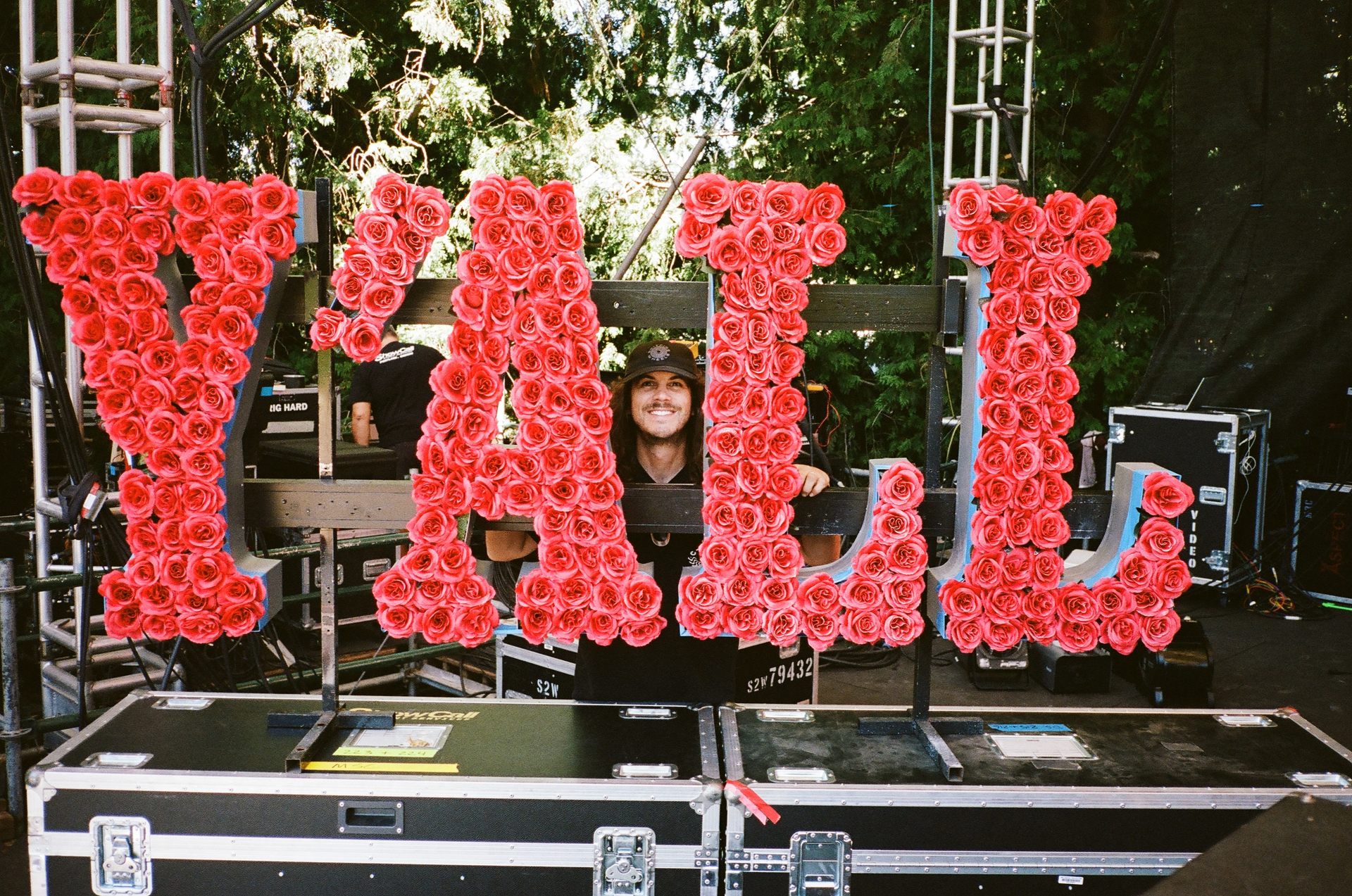 Photo of C.J. of C-Roll Productions smiling behind a wall of roses that spell 