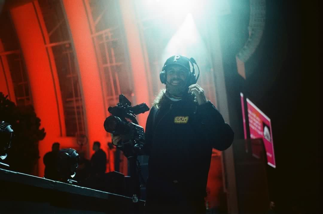 A man is standing in front of a camera in a dark room.