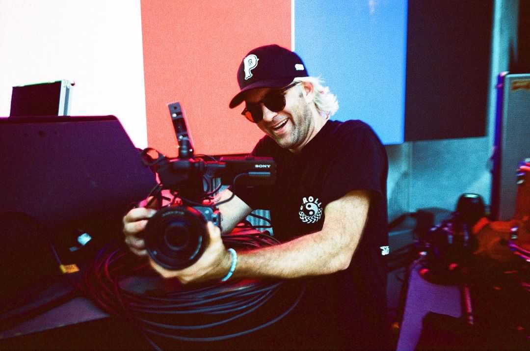 A man wearing a hat and sunglasses is holding a camera