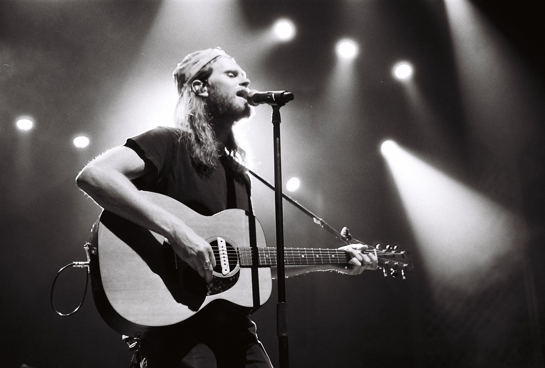 A man singing into a microphone while playing a guitar