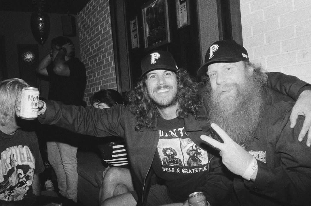 Two men with long beards are posing for a picture in a black and white photo.