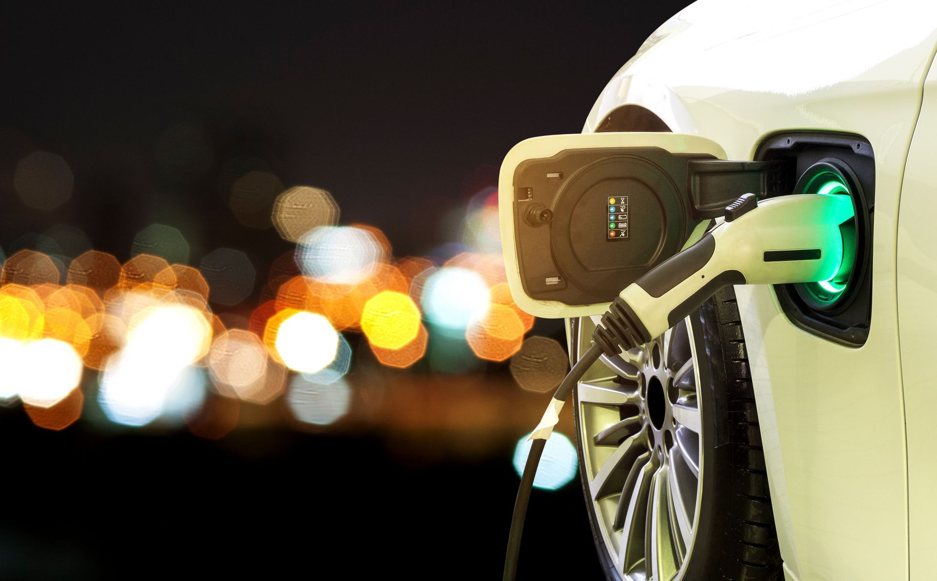 An electric car is being charged at a charging station at night.