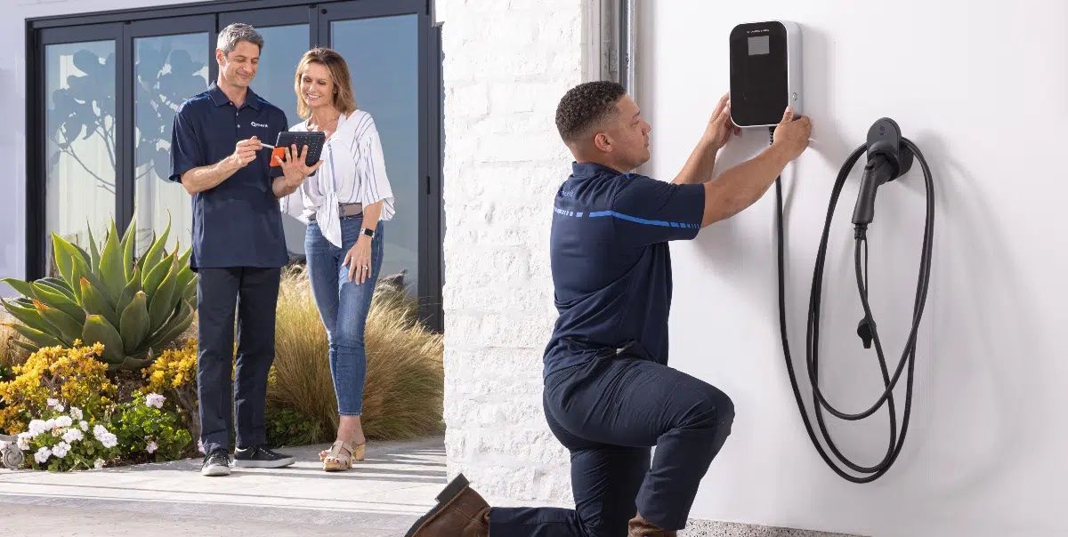 A man is installing an electric car charger on a wall.