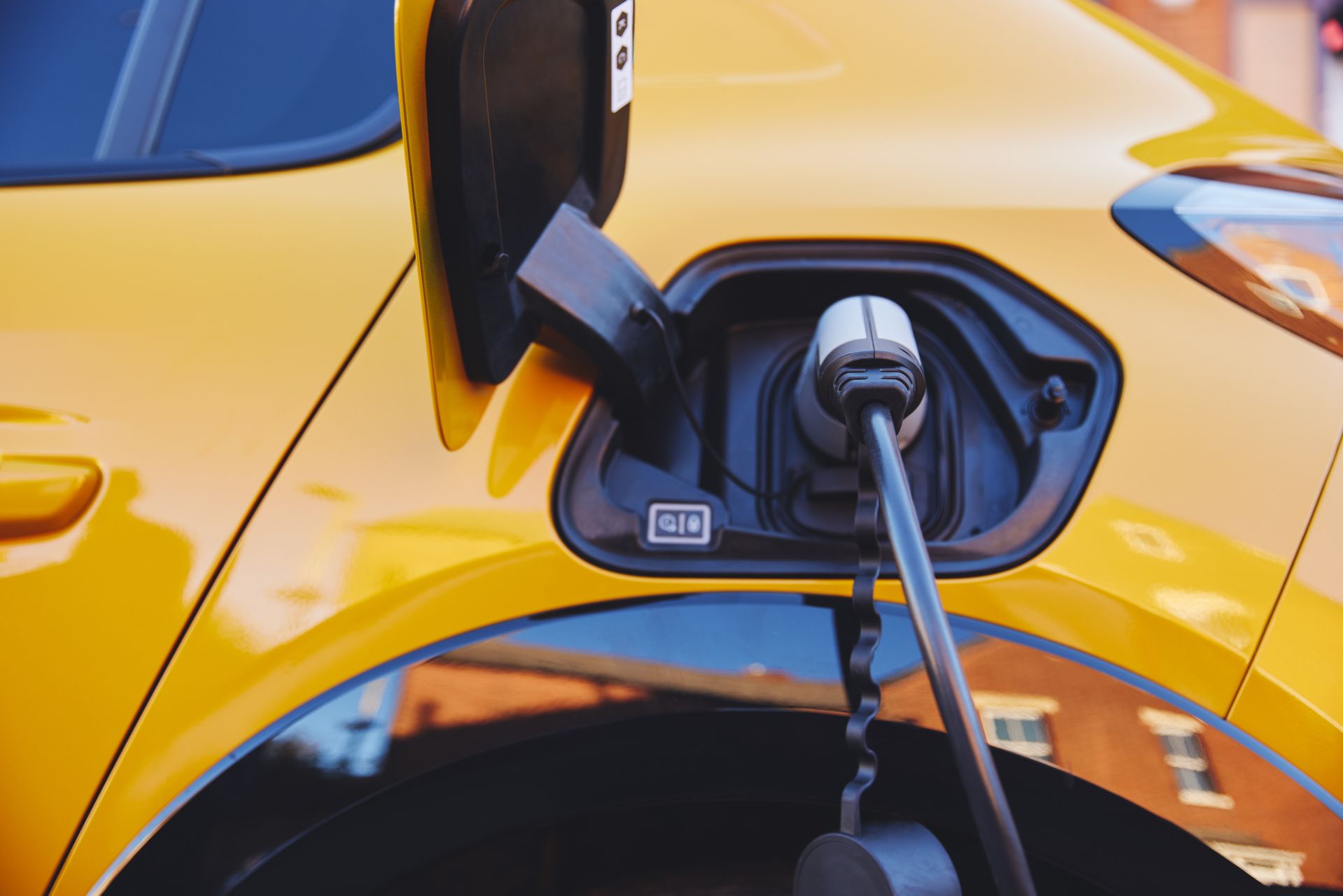 A close up of a yellow electric car being charged.