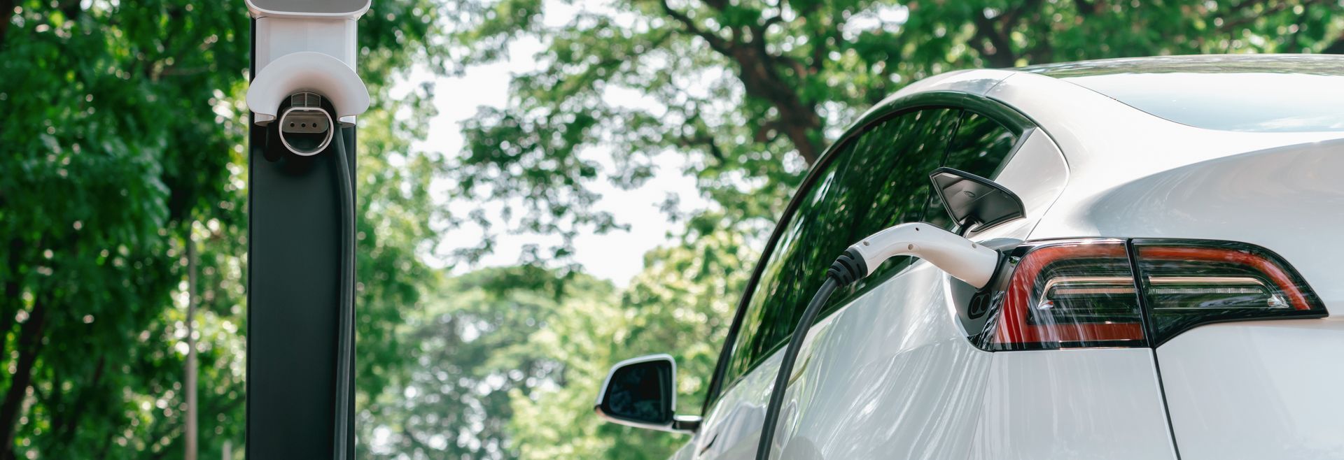 A white electric car is being charged at a charging station.