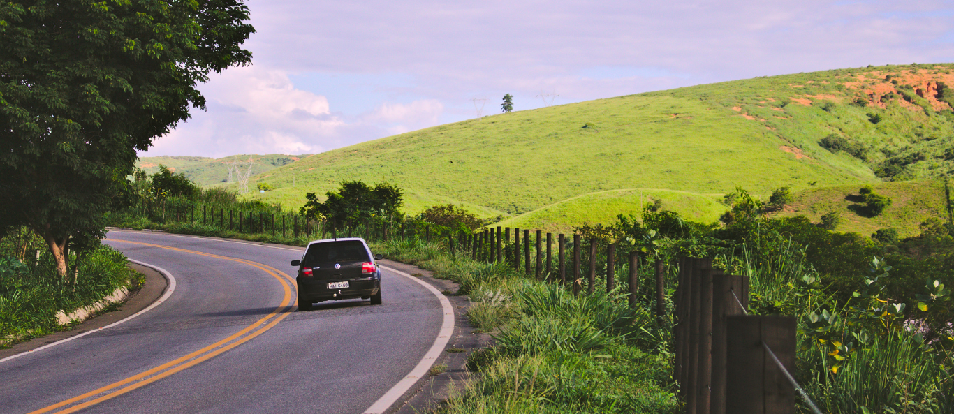 A car is driving down a curvy road in the countryside.