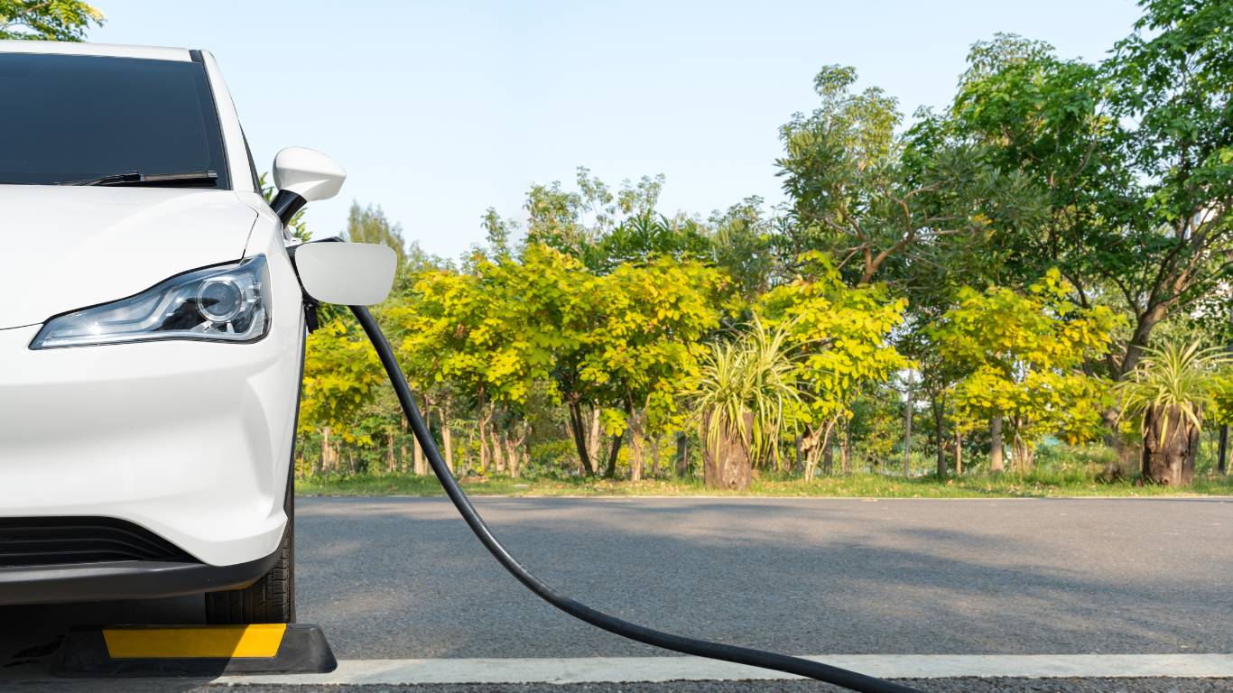 A white electric car is being charged on the side of the road.