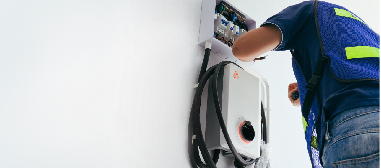 A man is installing an electric car charger on a wall.