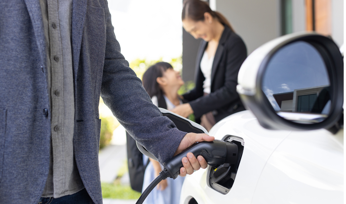 A man is charging an electric car at a charging station.