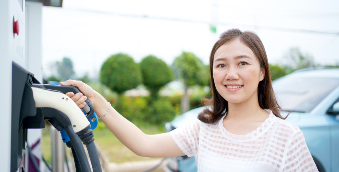 A woman is charging her electric car at a charging station.