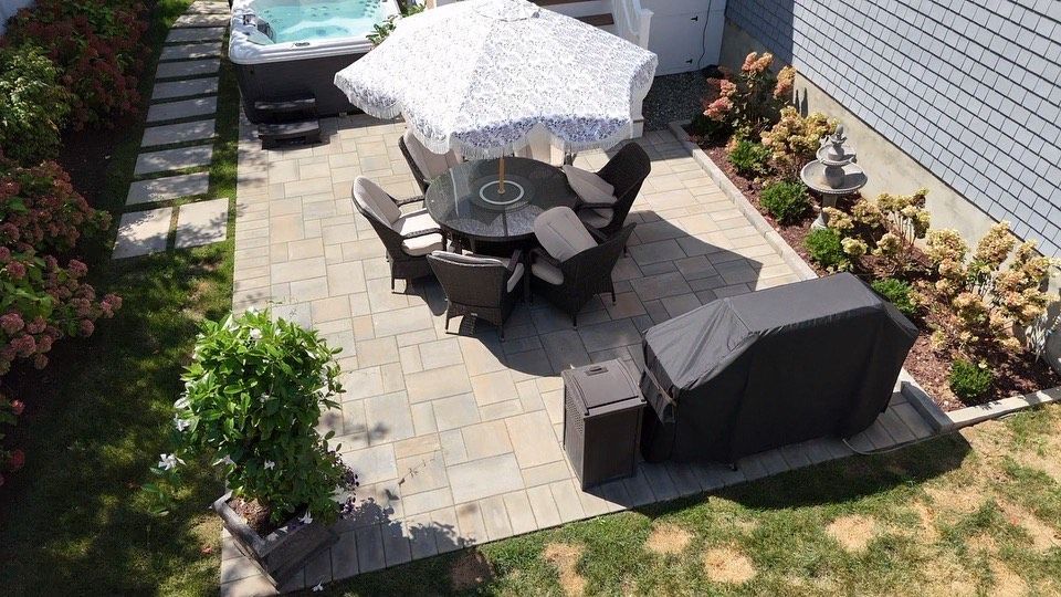 Patio with a round table, chairs, umbrella, hot tub, and grill.