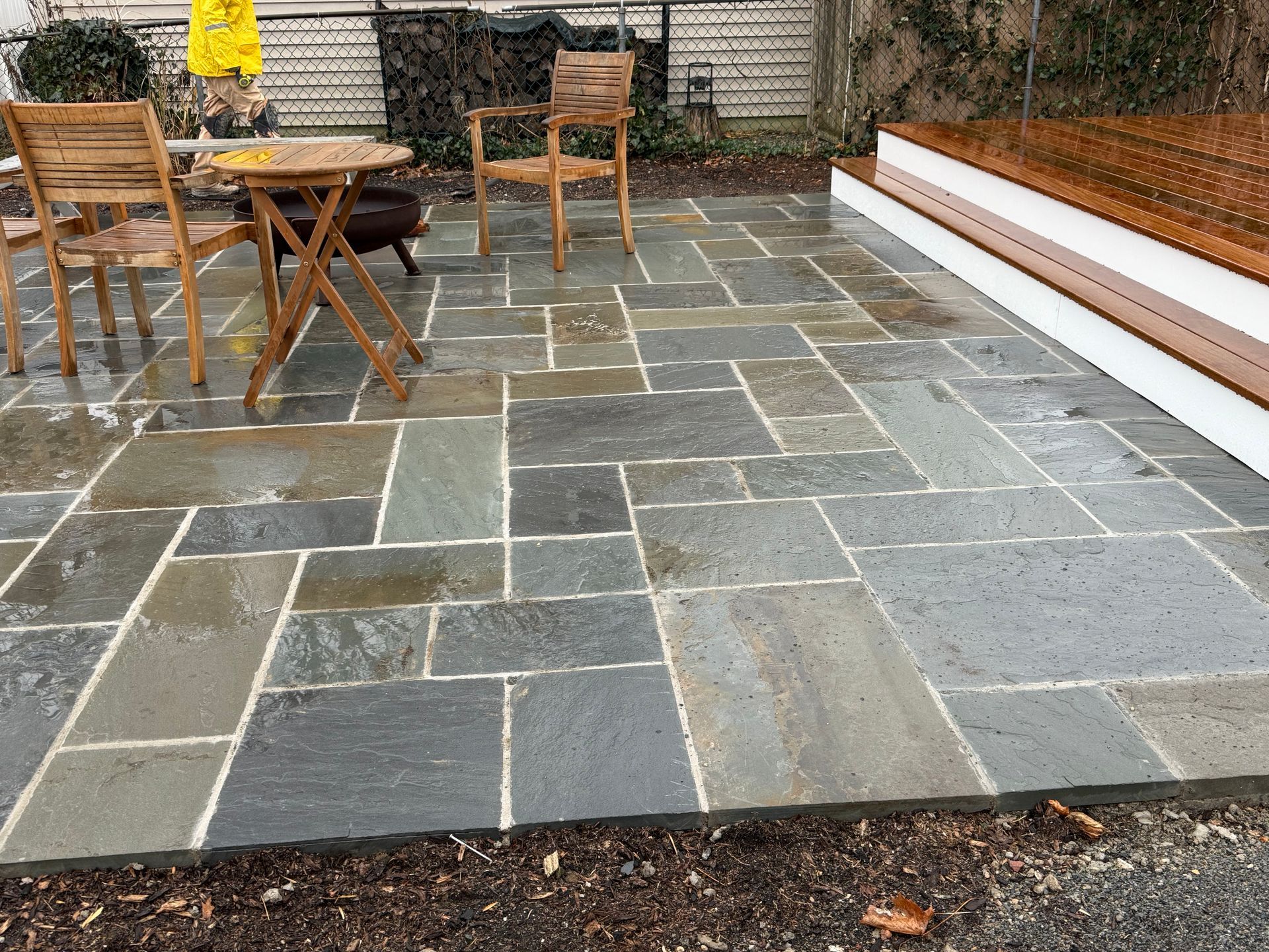 Stone patio with wooden furniture and built-in bench.