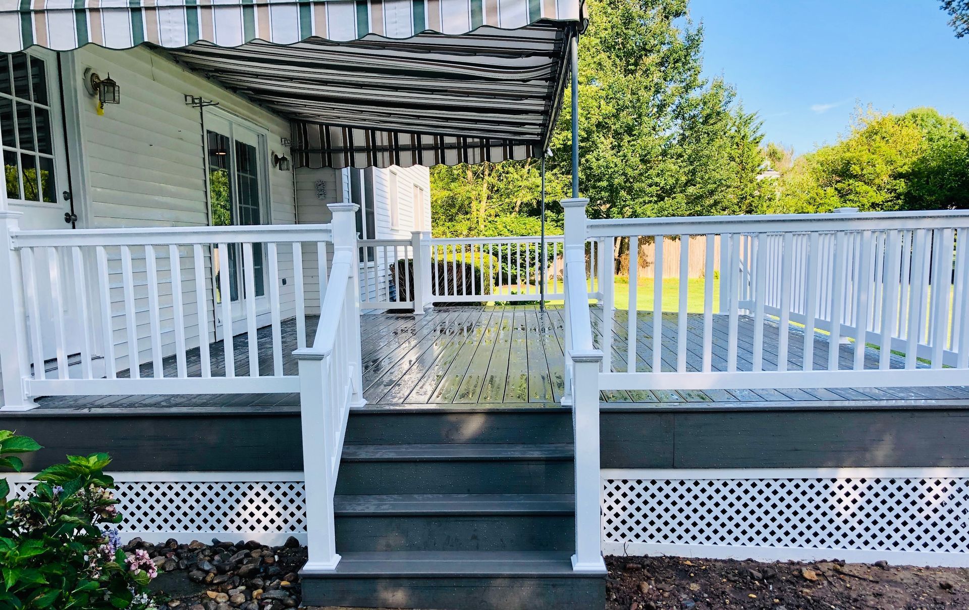 White deck with steps and railing, grey decking, and awning.