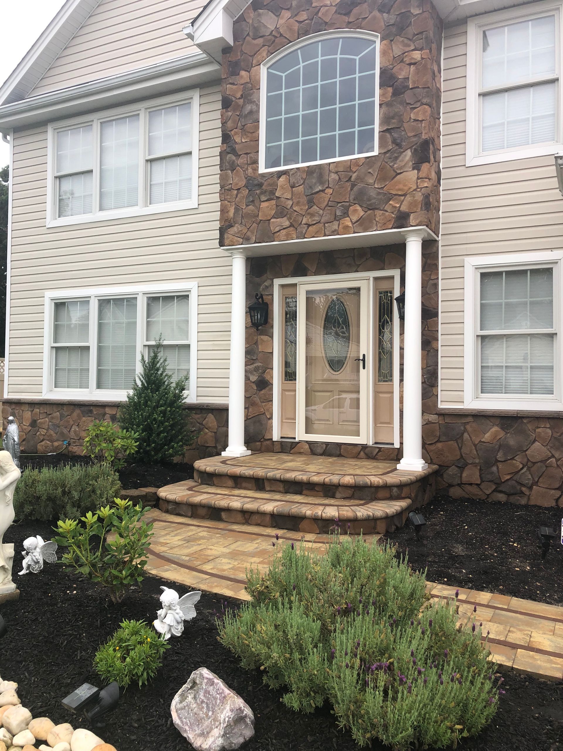 House exterior with stone facade around the front door. Landscaping with walkway and shrubs leads to the entrance.