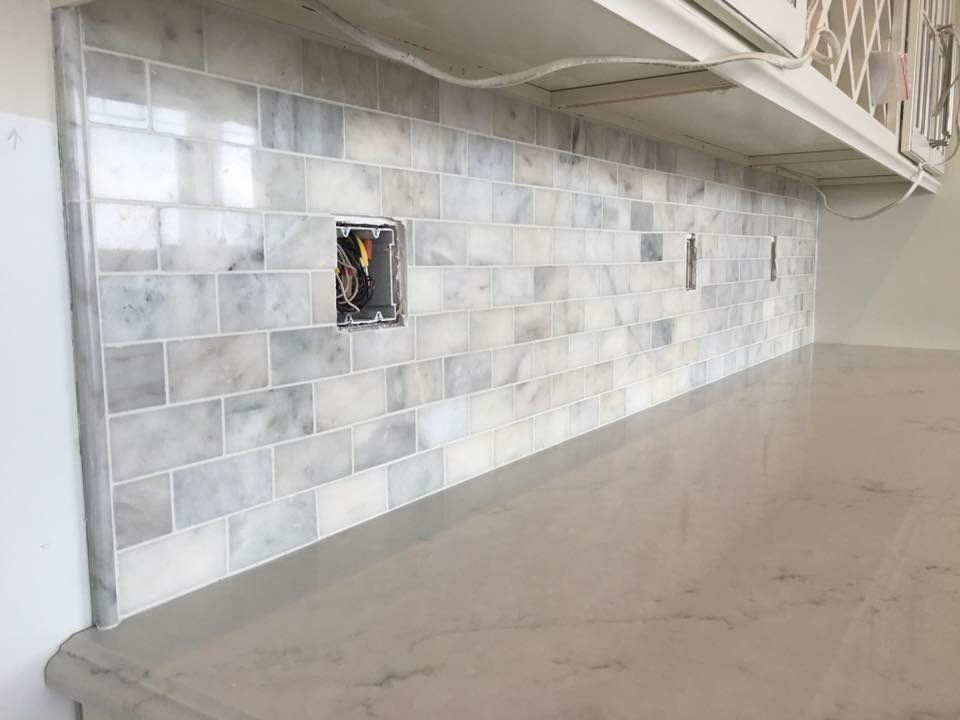 Gray marble backsplash with electrical outlets and a light gray countertop.