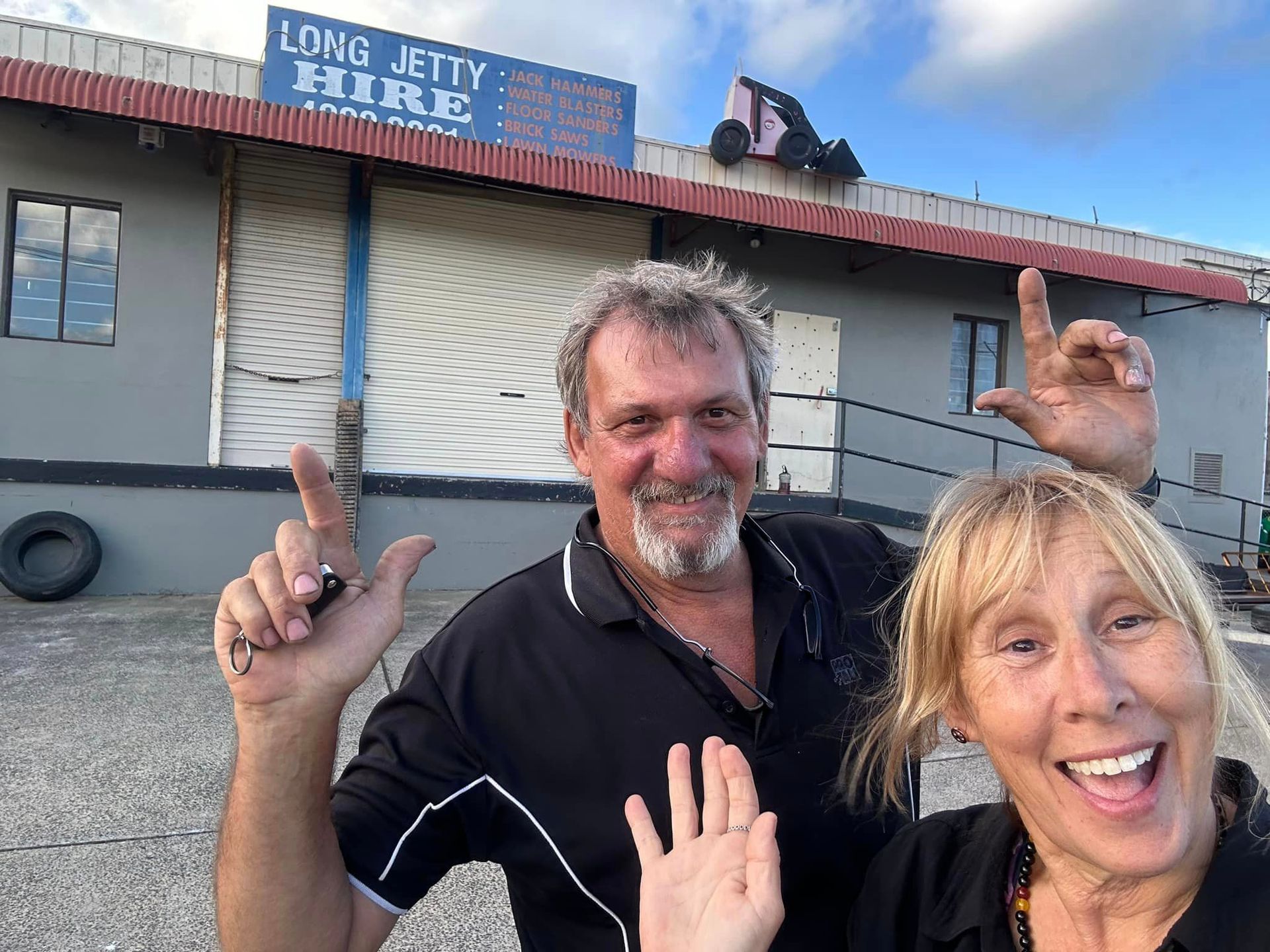 A Man And A Woman Are Standing In Front Of A Long Jetty Hire Building – Central Coast, NSW - Long Jetty Hire