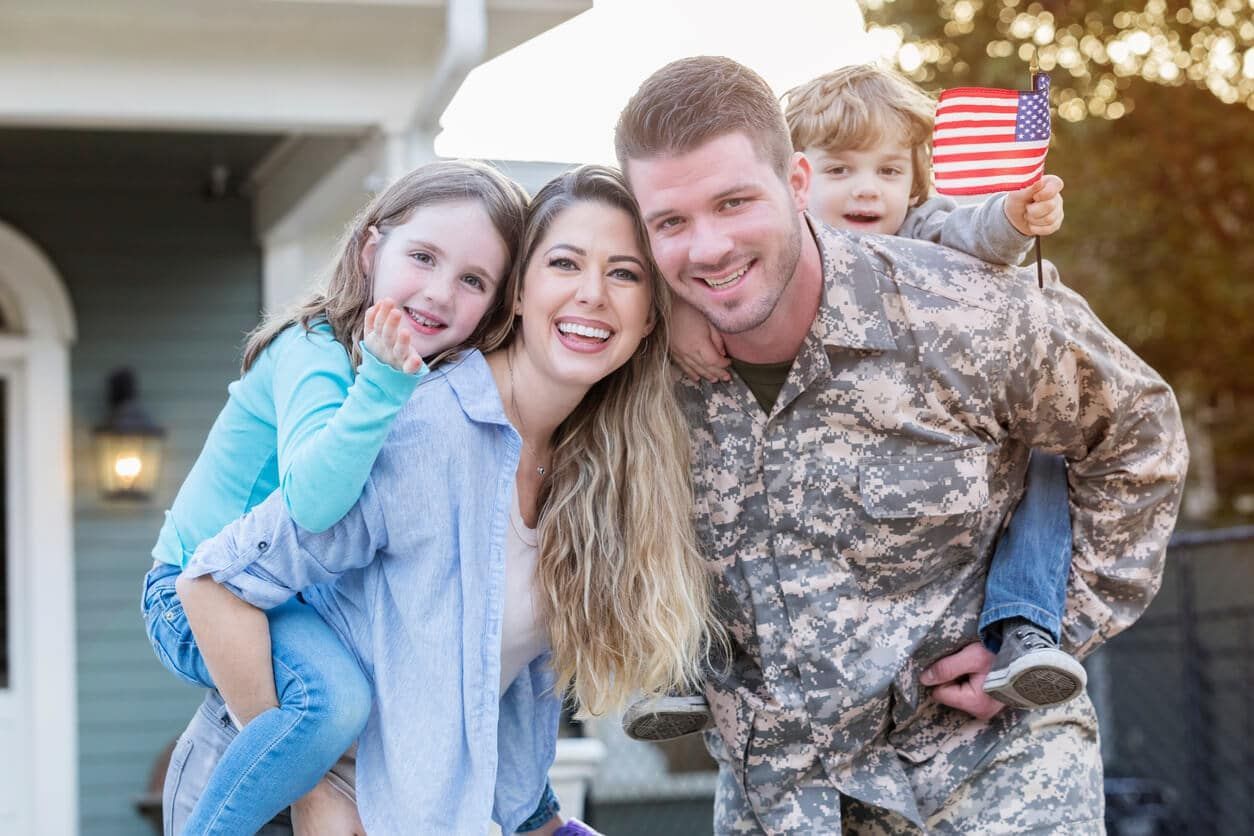 A man in a military uniform is posing for a picture with his family.