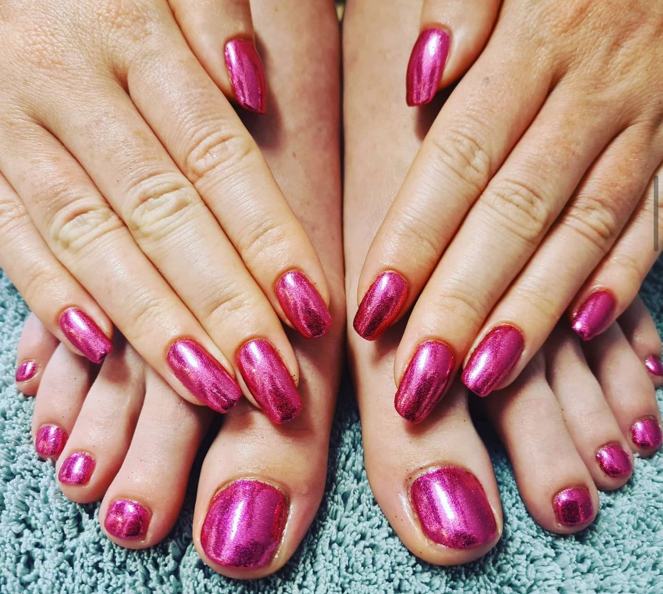 A woman 's hands and feet with pink nail polish done at a beauty salon