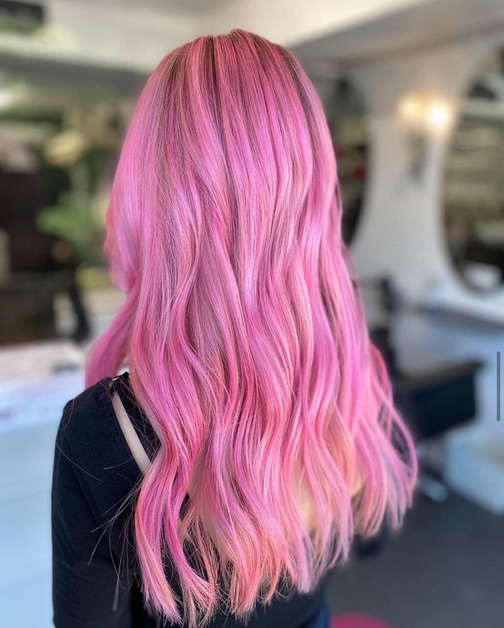 A woman with long pink hair is wearing a black shirt. Her hair has been professionally coloured at Panache Hair salon in Dunstable