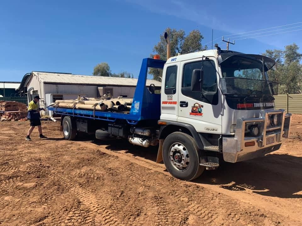 A Tow Truck With A Flat Bed Is Parked In A Dirt Field — Territory Towing & Transport In Alice Springs, NT