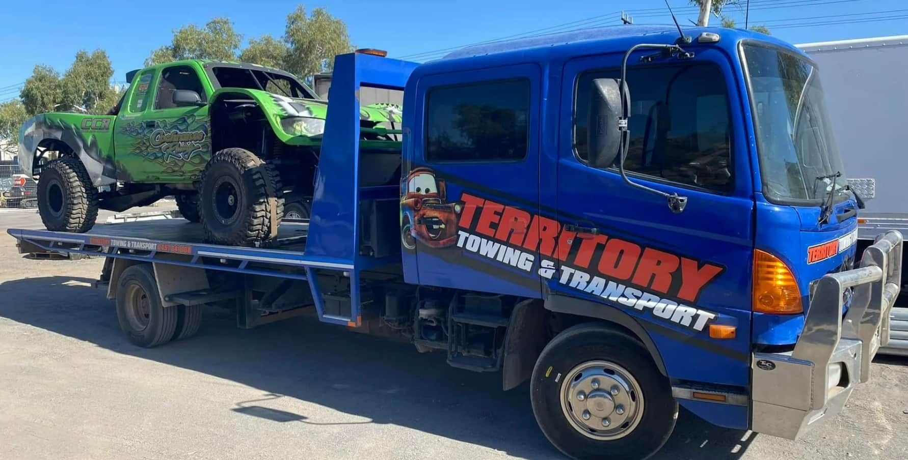 A Blue Tow Truck Is Towing A Green Atv — Territory Towing & Transport In Alice Springs, NT