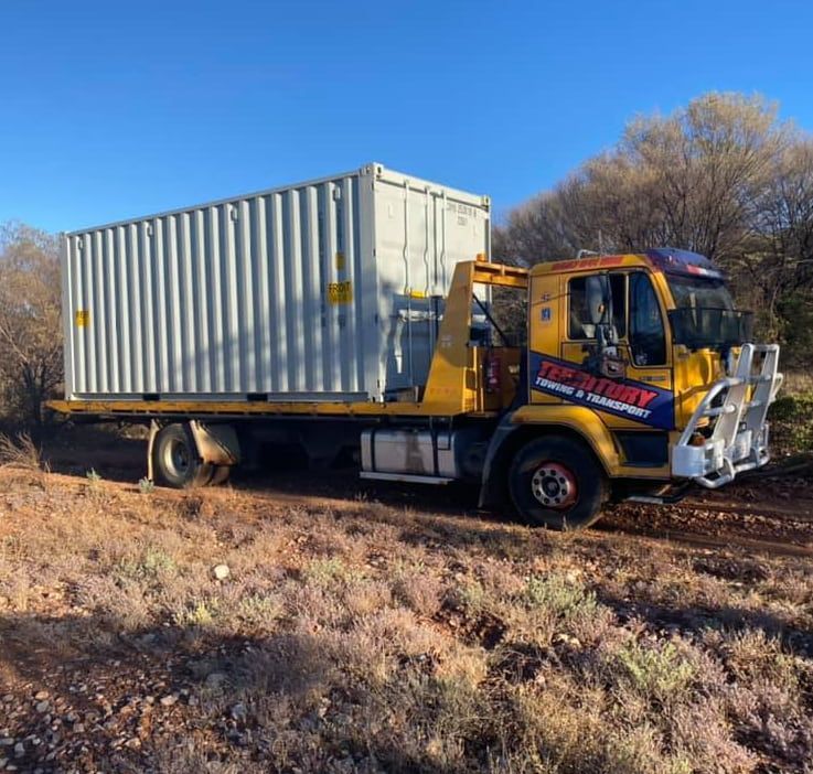 A Tow Truck With A Container On The Back Is Parked On A Dirt Road — Territory Towing & Transport In Alice Springs, NT