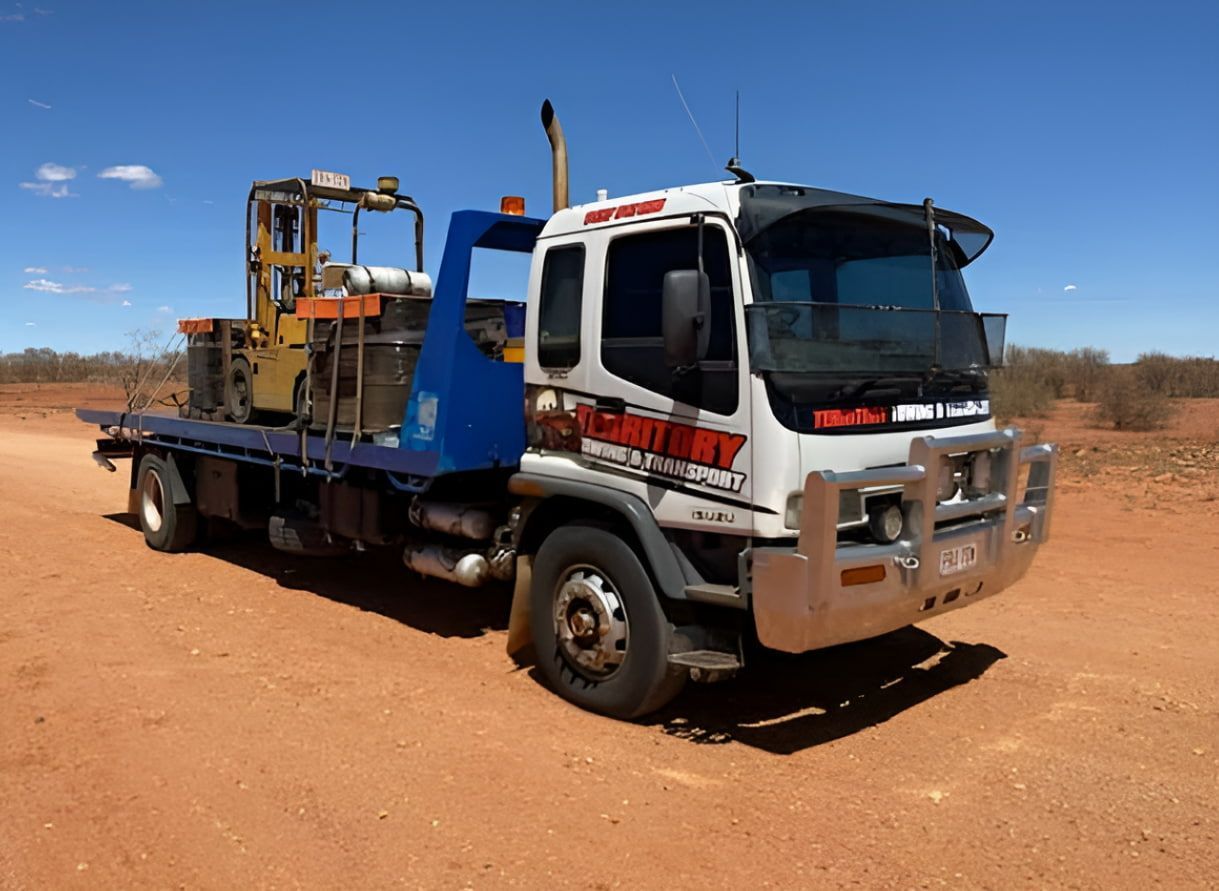 A Tow Truck Is Carrying A Bulldozer On The Back Of It — Territory Towing & Transport In Alice Springs, NT