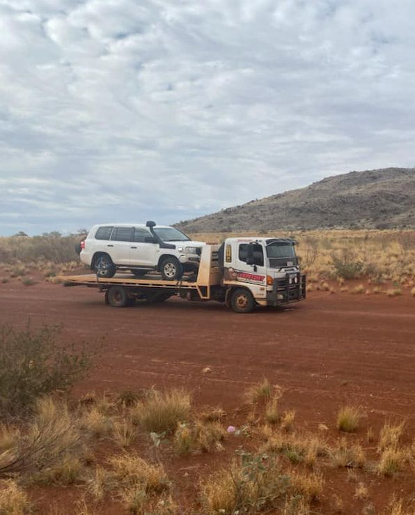 A White Suv Is Being Towed By A Tow Truck In The Desert — Territory Towing & Transport In Alice Springs, NT
