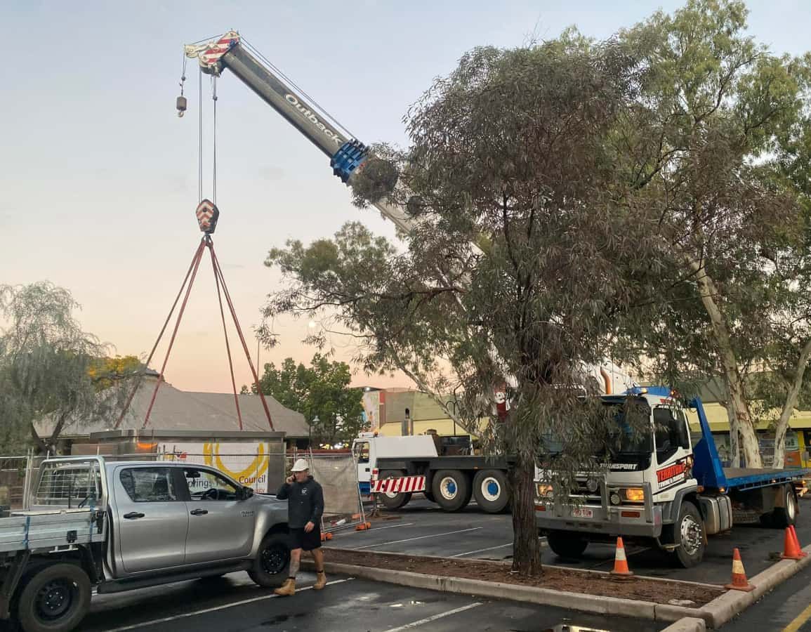 A Truck Is Being Lifted By A Crane In A Parking Lot — Territory Towing & Transport In Alice Springs, NT