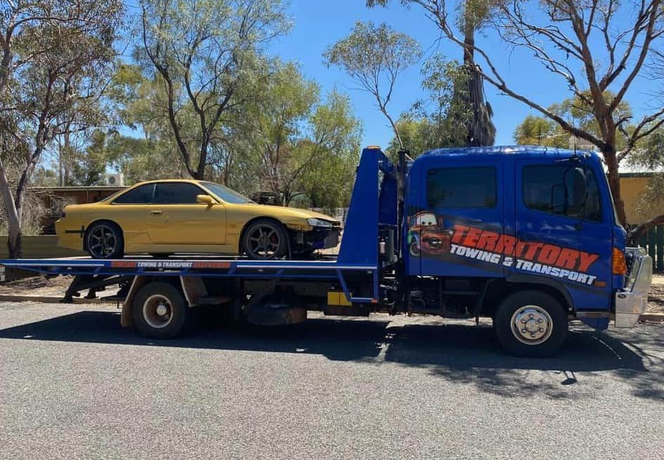 A Yellow Car Is Sitting On Top Of A Blue Tow Truck — Territory Towing & Transport In Alice Springs, NT